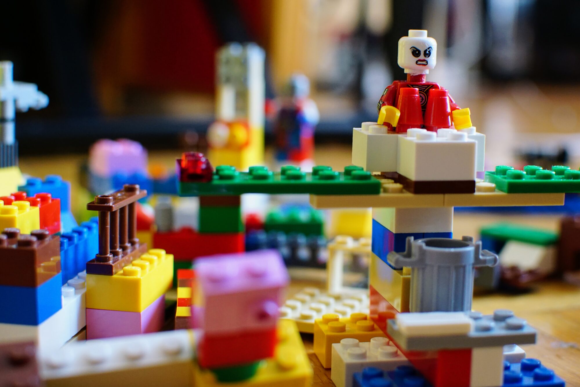 A scowling Lego minifigure standing guard on top of a sprawling, many-coloured Lego city